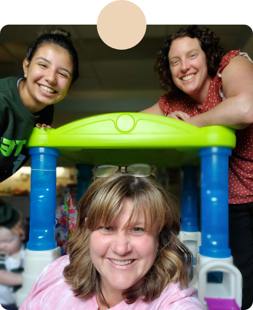 3 smiling caregivers posing in a playroom